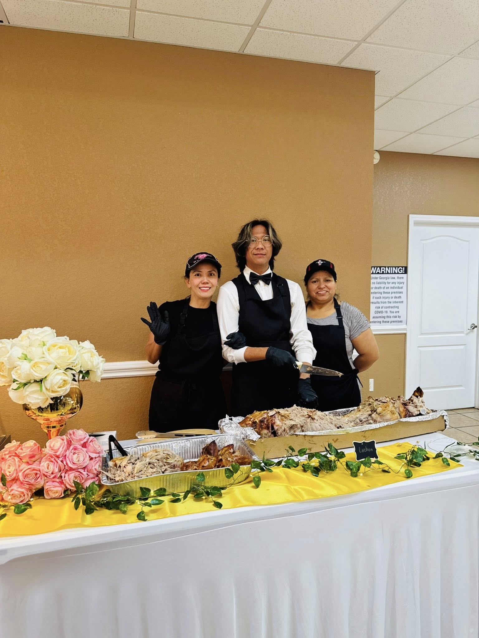 Lor's catering team standing behind a decorated event table with Filipino food trays